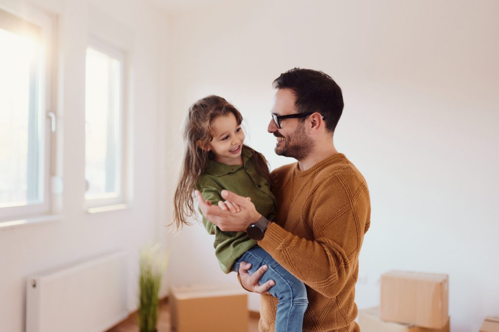 Carefree father and daughter dancing at their new apartment.