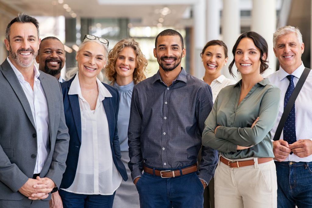 Smiling team of employees in a modern office, representing a limited company offering life insurance benefits to support staff wellbeing and retention.