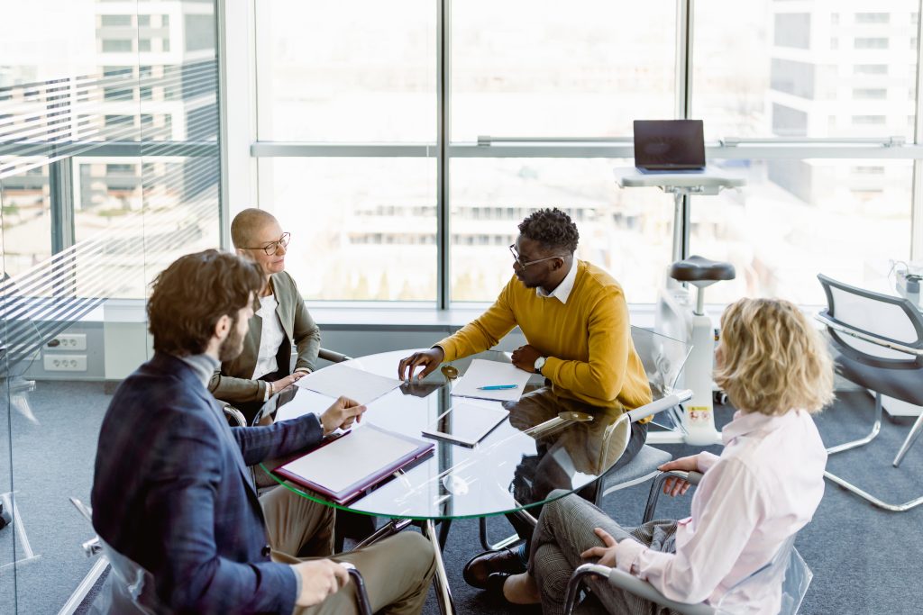 Group of professionals in a modern office discussing business strategy around a table, representing planning for tax-efficient business life insurance.