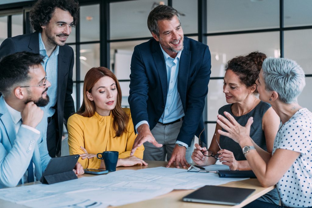 Group of architects cooperating while examining blueprints on a meeting in the office. Group of business persons in business meeting. Group of entrepreneurs on meeting in board room. Creative business team on meeting in the office.