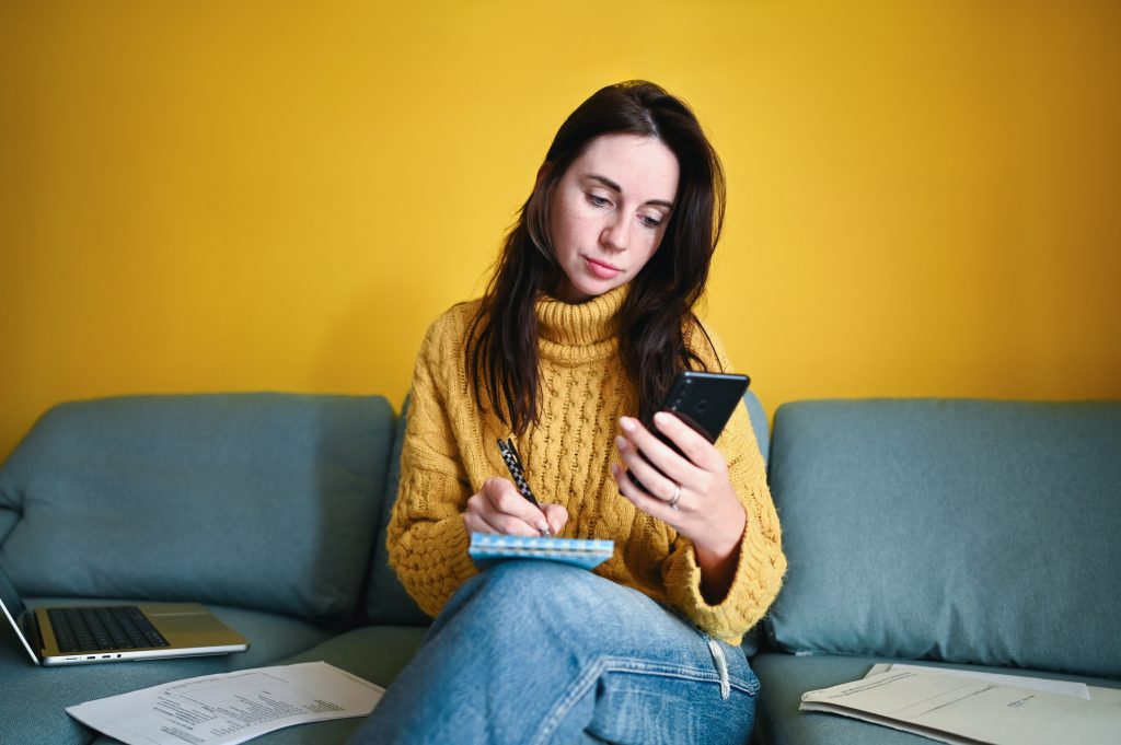 Mid adult woman reviewing their taxes while using mobile phone.